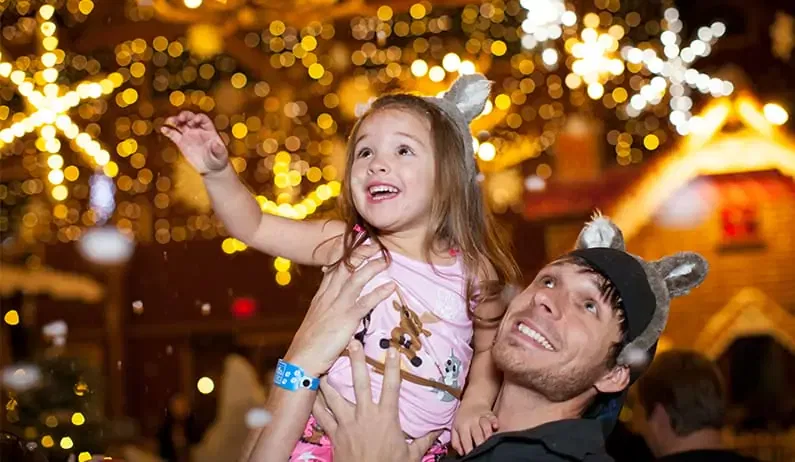 Dad holding little girl while it snows